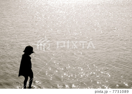 女の子 海 後ろ姿 夕暮れの写真素材