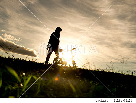 男性 夕焼け 後ろ姿 眺めるの写真素材