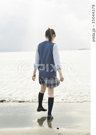 女子高生 後ろ姿 制服 波の写真素材