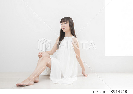 女性 ワンピース 座る 見上げるの写真素材