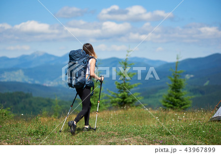 Sporty Woman Hiker with Backpack and Trekking Sticks Hiking in the