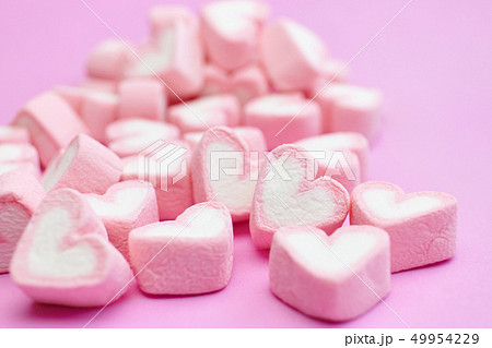 Waffle cone with heart-shaped marshmallows, close-up on a blue