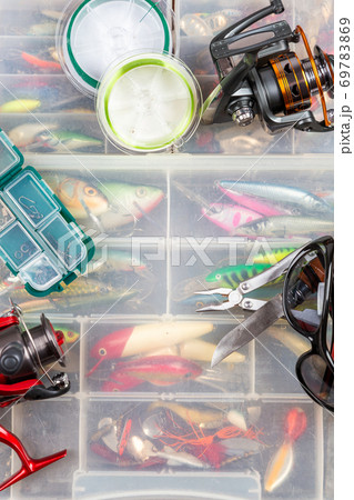 Various Fishing Lures in Plastic Box on Wooden Background