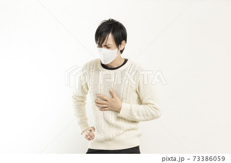 マスク姿の男性/頭痛で頭を抱える/具合が悪い独身男性/	