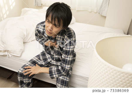 昨日の飲み会が遅くまで続き、朝胸焼けが酷く起きれないパジャマ姿の男性