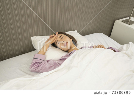 病気で寝込んでいる女性/体調の悪い女性/ベットに寝ている美しい女性