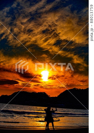 海 夕焼け 女の子 波打ち際の写真素材