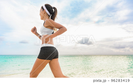 Female runner on beach with sports bra and shorts. Midsection